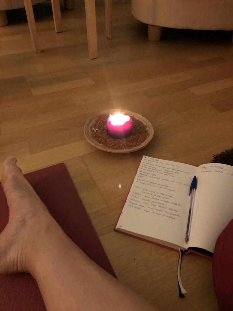 Mein Fuß auf einer Yogamatte, eine Kerze und ein Journal. 