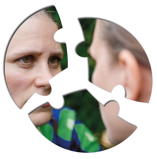 Gehalten in einer Gruppe Eine Nahaufnahme des Gesichts einer Person, das in vier Puzzleteile zerlegt ist. Die Person betrachtet ihr Spiegelbild. Das Bild hat einen grünen, natürlichen Hintergrund, und die Puzzleteile sind durch weiße Ränder getrennt.