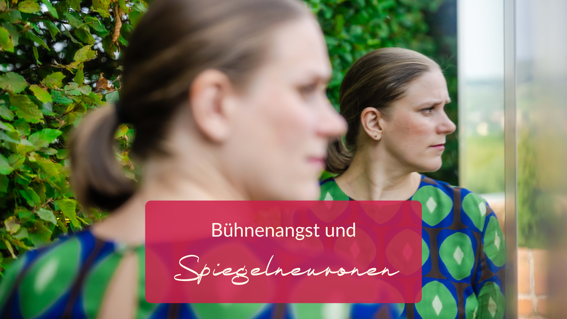 Bühnenangst Eine Frau mit ernstem Gesichtsausdruck betrachtet ihr Spiegelbild in einer Glaswand. Sie steht im Freien im Grünen. Der eingeblendete Text lautet: „Bühnenangst und Spiegelneuronen“ und deutet auf die Auswirkungen von Lampenfieber auf die Selbstwahrnehmung hin.